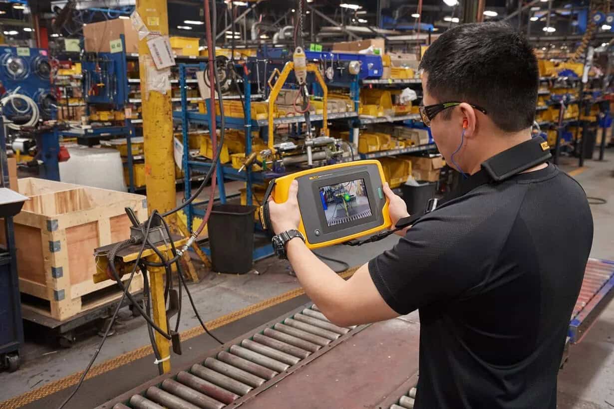 Technician using Fluke Acoustic Imager to detect gas leaks on a factory production line for maintenance