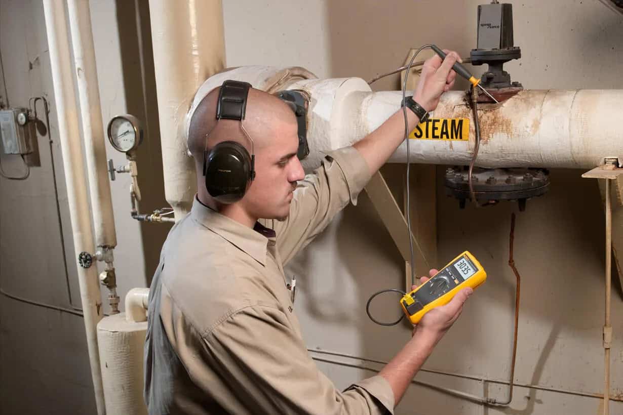 Professional technician using Fluke 179 for control panel diagnostic and electrical troubleshooting.