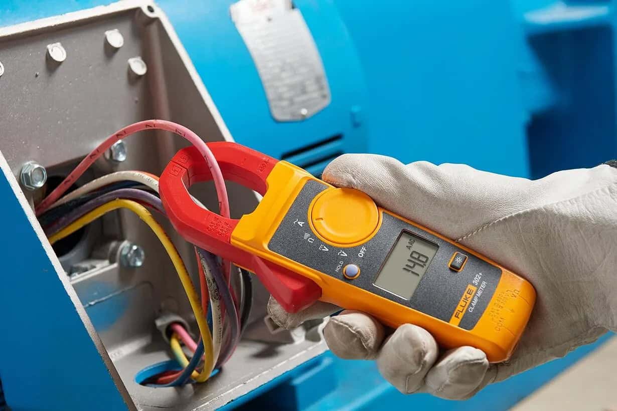 Fluke 302+ clamp meter measuring AC current in a control box