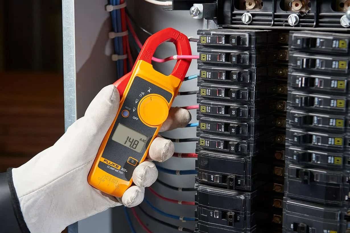 Fluke 302+ clamp meter measuring current in a standard breaker box, showing its typical application limit