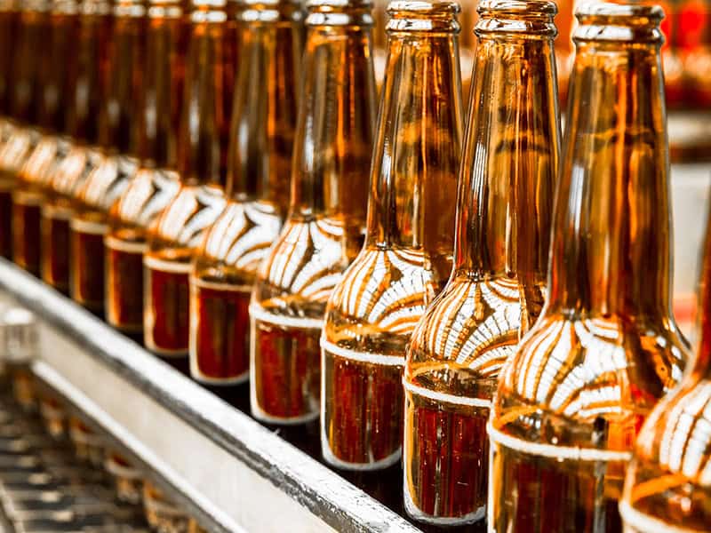 Coated industrial chains driving glass bottle conveyor line in food and beverage operating environment